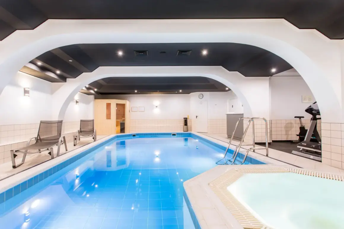 Basen i jacuzzi w hotelu Qubus Wrocław. Obok leżaki, sauna i sprzęt do ćwiczeń.