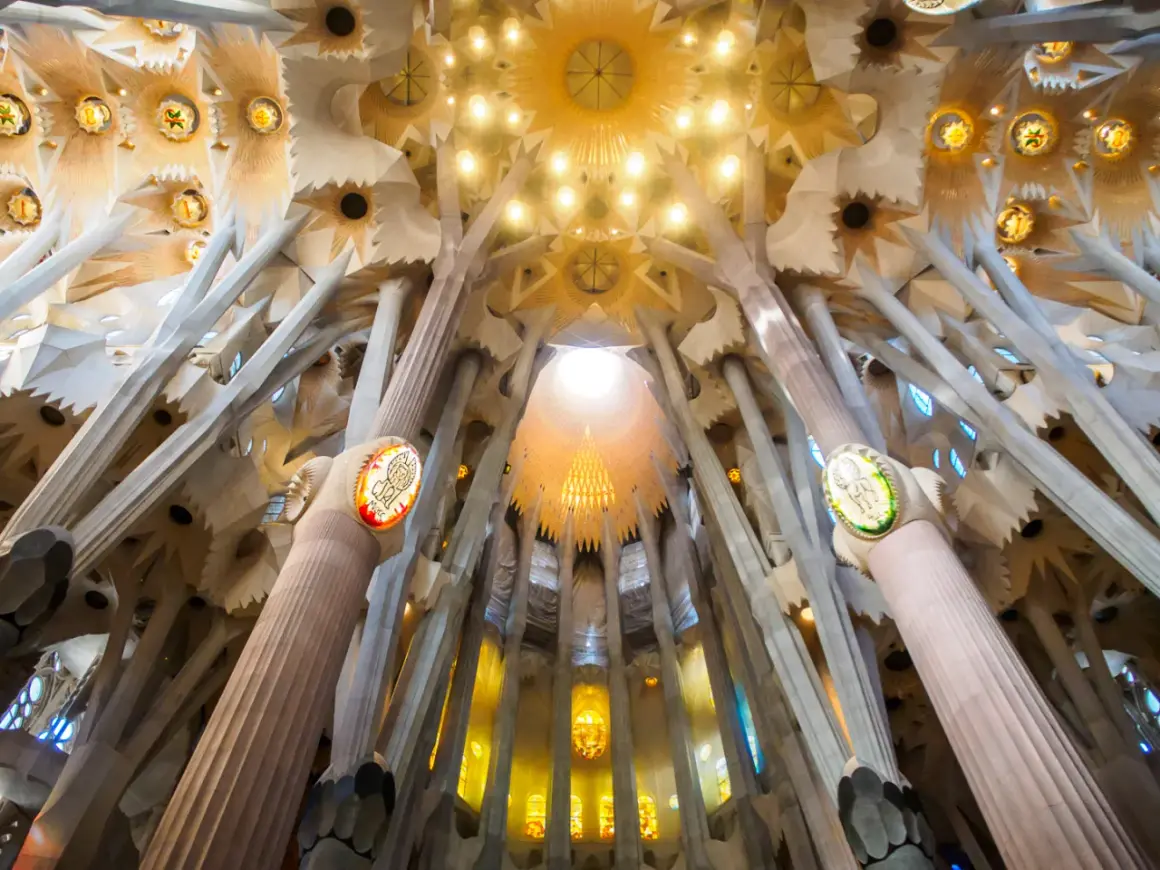 Wnętrze Sagrada Familia zachwyca drzewiastymi kolumnami i witrażami.