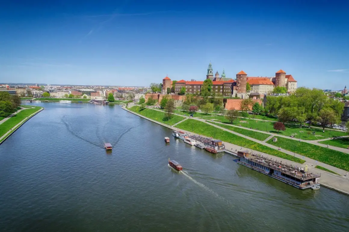 Widok na Wawel i Wisłę, najdłuższą rzekę w Polsce, z łodziami pływającymi po wodzie.