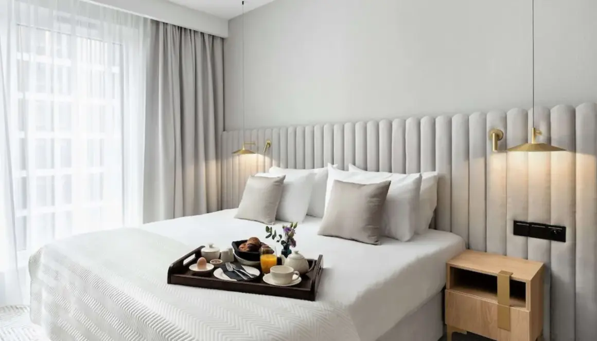 Eleganckie łóżko w pokoju hotelowym, śniadanie na tacy, jak w Royal Tulip Warszawa.