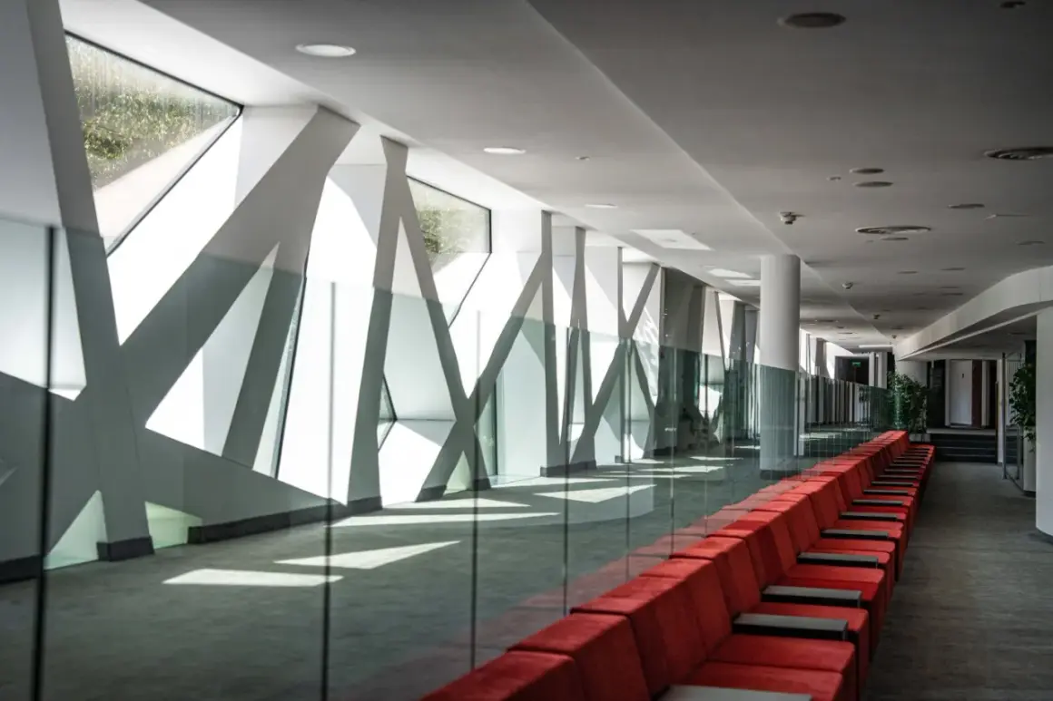 Nowoczesny korytarz z czerwonymi kanapami i geometrycznymi oknami. Hotel Narvil Conference & Spa opinie – idealne miejsce na wydarzenia.