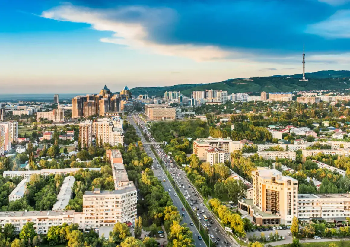 Widok na Almaty, dawną stolicę Kazachstanu, z wieżą telewizyjną w tle i ruchliwą autostradą pośród zieleni.