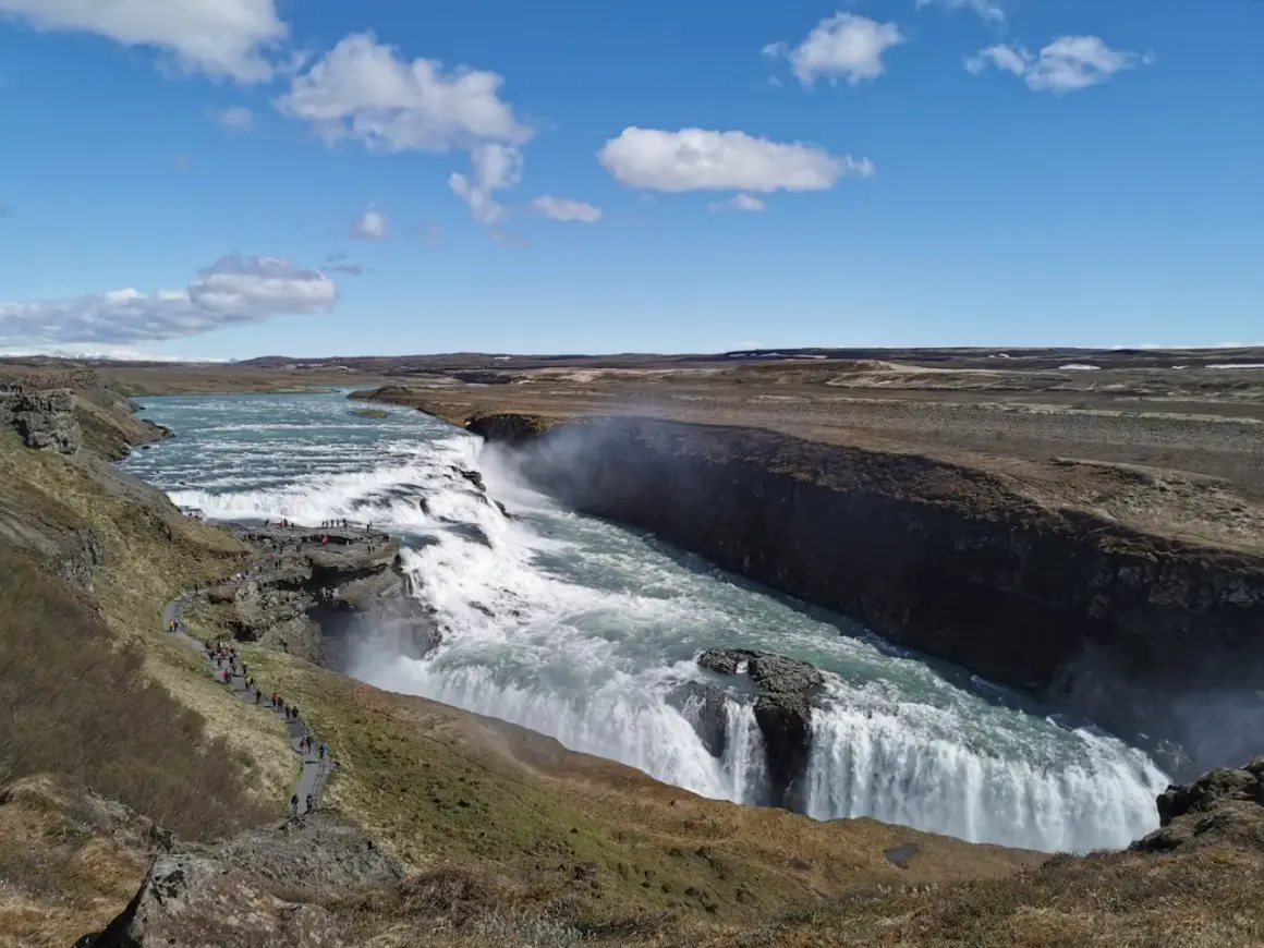 Potężny wodospad Gullfoss, część islandzkiego Złotego Kręgu, z turystami na ścieżce widokowej.