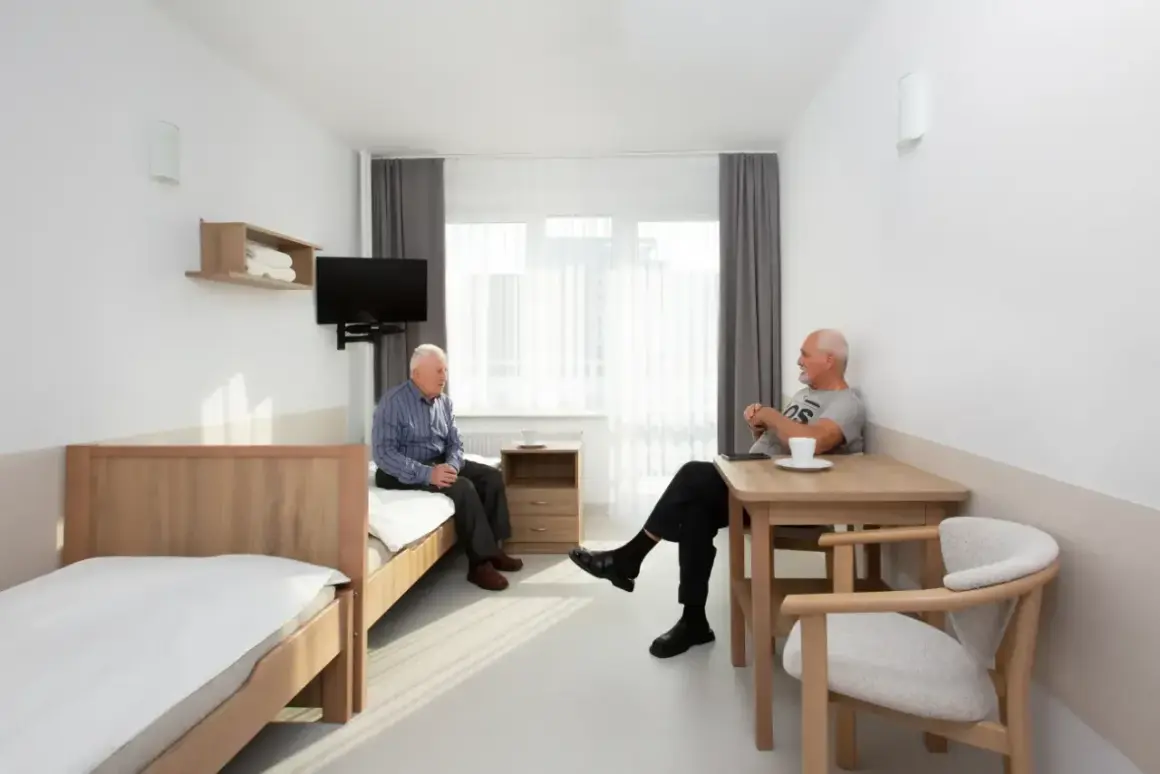 Dwóch starszych panów rozmawia w pokoju sanatorium MSWiA Sopot. Opinie o tym miejscu są pozytywne.