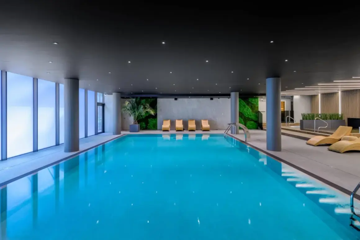 Basen w AC Hotels Krakow. Relaks przy basenie z widokiem na zielone ściany i nowoczesne leżaki.