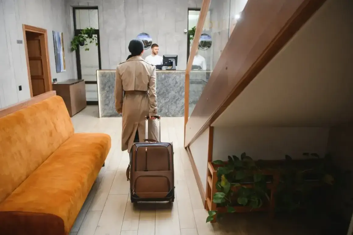Kobieta z walizką idzie do recepcji. Czy to początek udanego pobytu, jak sugerują pozytywne zenhotels recenzje?