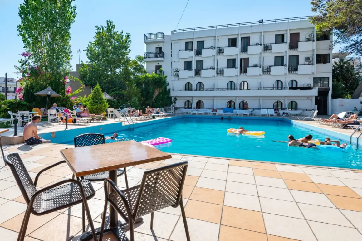 Basen hotelowy, ludzie relaksują się na leżakach i pływają. Wiele pozytywnych heronissos hotel opinie potwierdza ten widok.