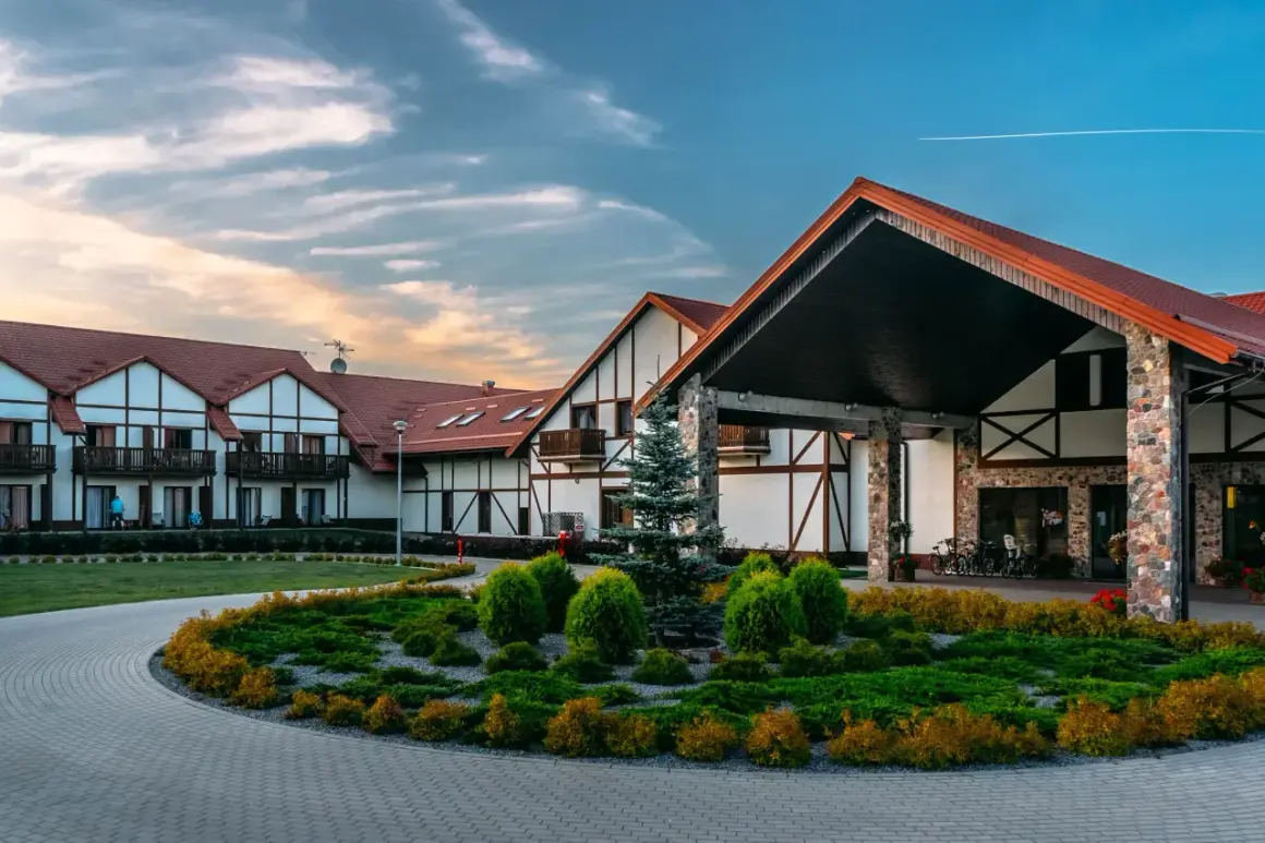 Hotel Mikołajki Leisure & Spa: malowniczy budynek z kamiennymi elementami i drewnianą stolarką, otoczony zadbanym ogrodem.