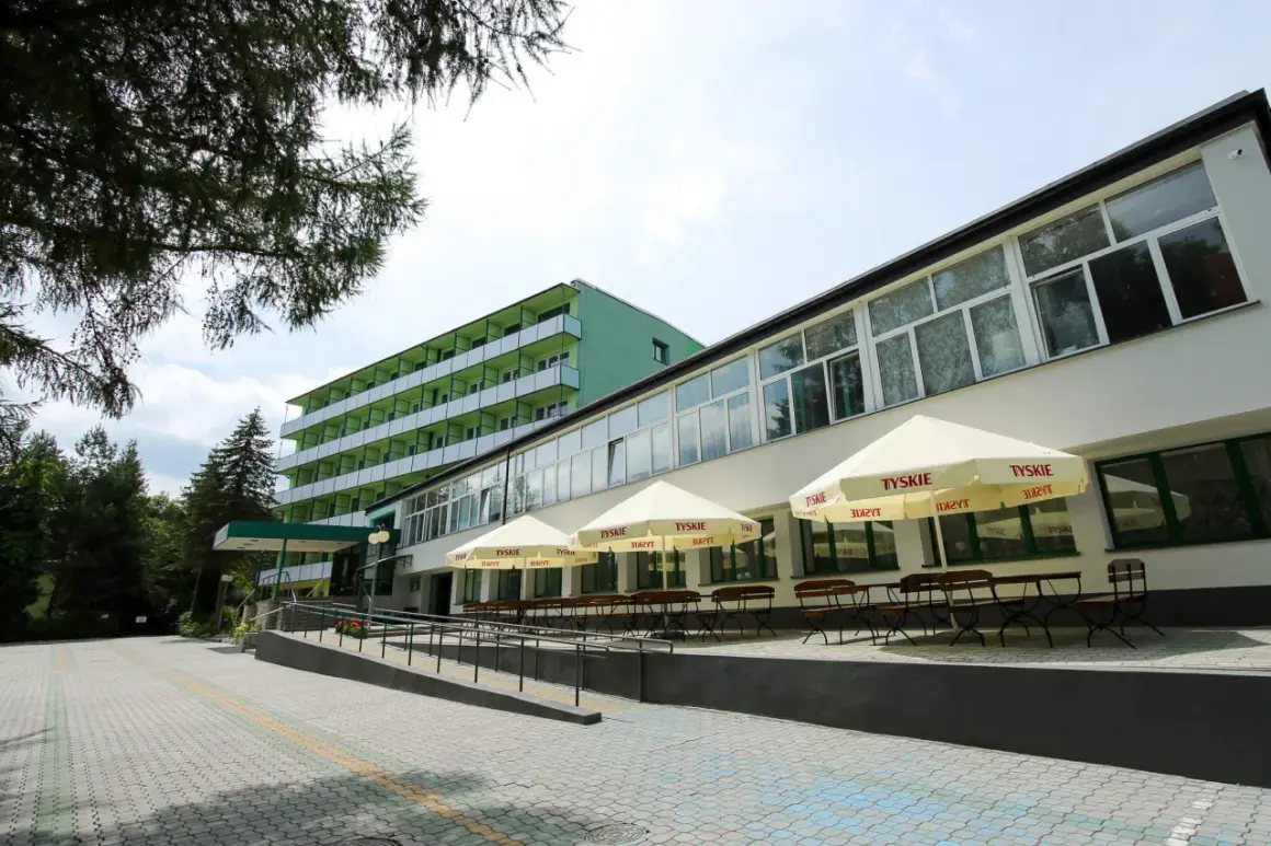 Zielone sanatorium z balkonami i tarasem z parasolami. Idealne miejsce na tanie sanatorium prywatnie.