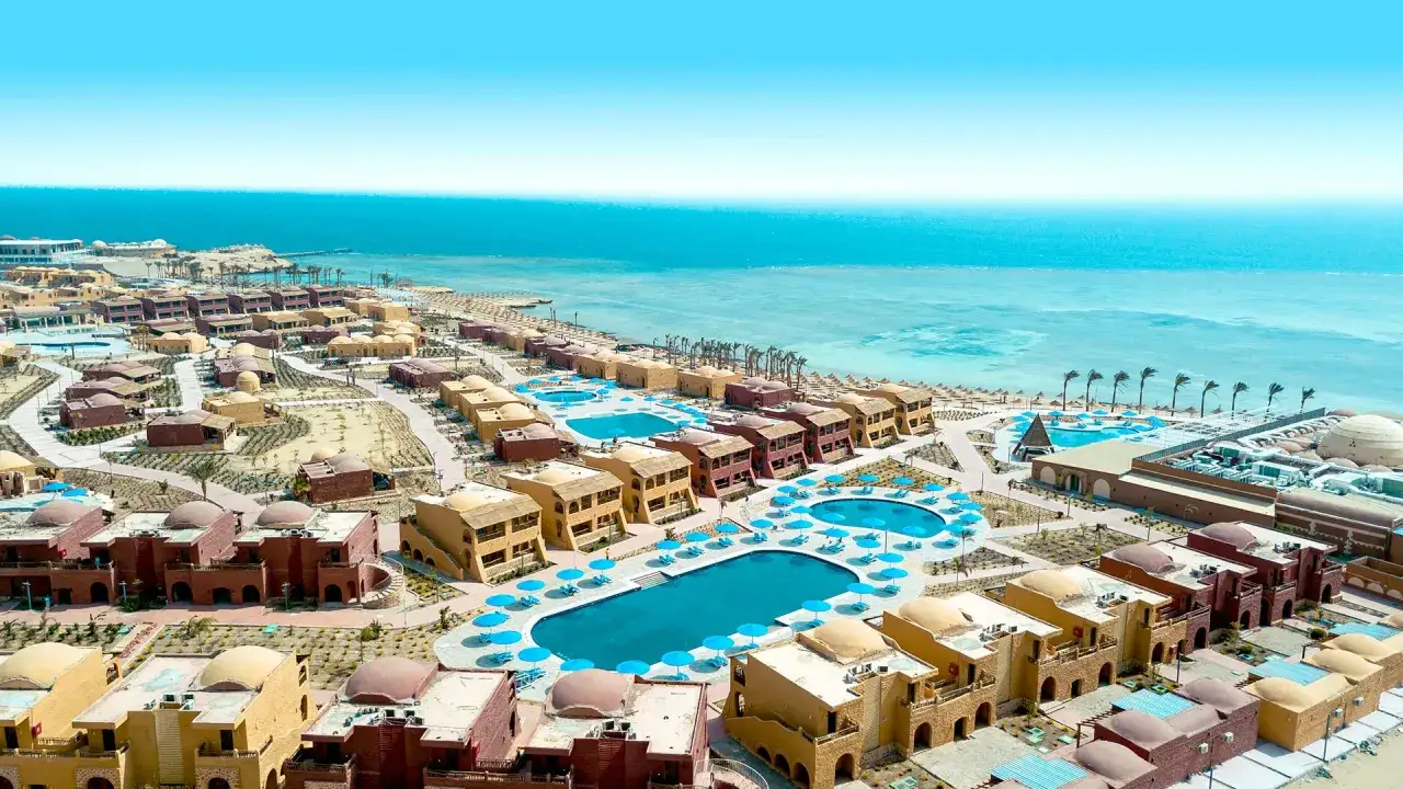 Widok z lotu ptaka na kompleks hotelowy Pickalbatros Marsa Alam z basenami i budynkami w stylu nubijskim, w tle turkusowe Morze Czerwone.