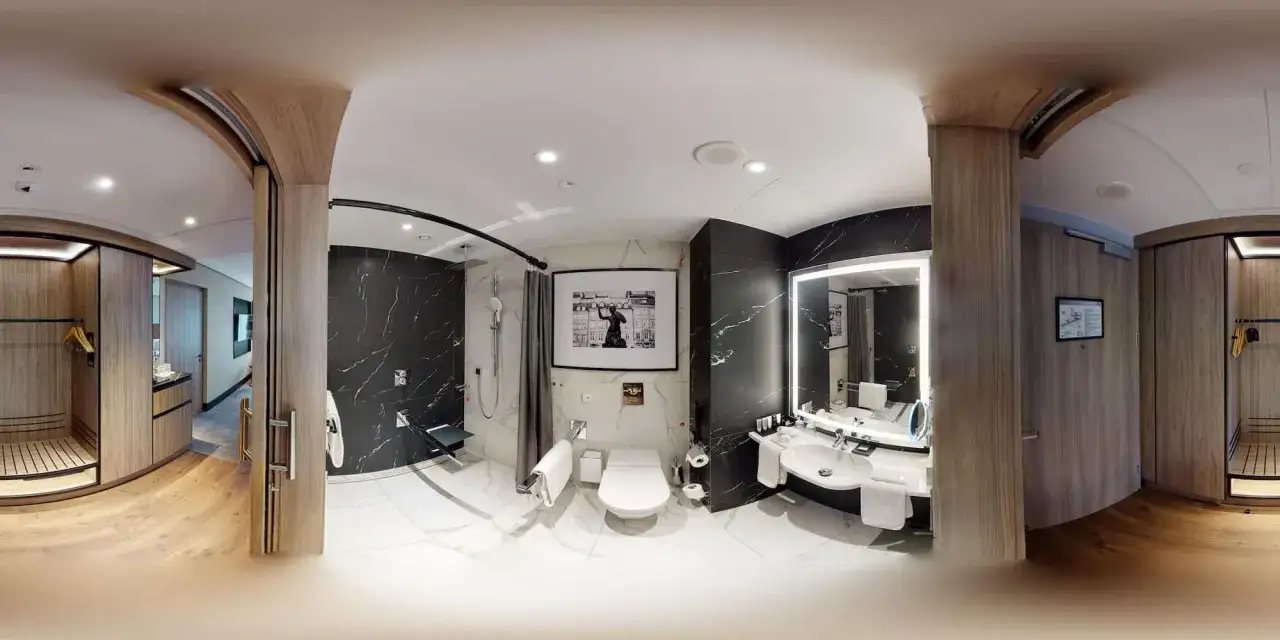 Nowoczesna łazienka w hotelu Radisson Collection Hotel Warsaw z czarnymi, marmurowymi akcentami, prysznicem, toaletą i umywalką.