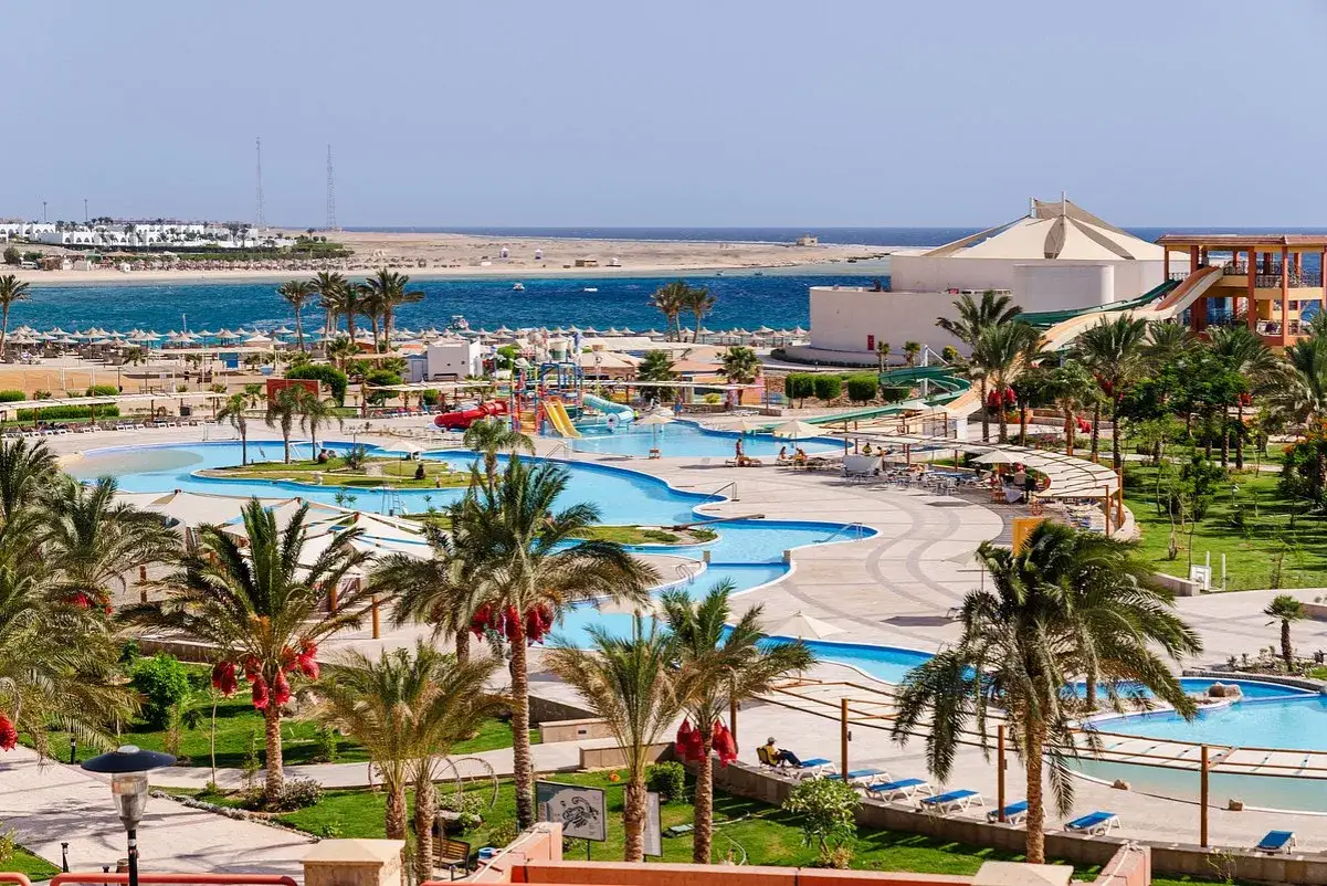 Basen z wodnymi zjeżdżalniami i palmami w Sataya Resort Marsa Alam. Opinie gości często podkreślają ten piękny widok.