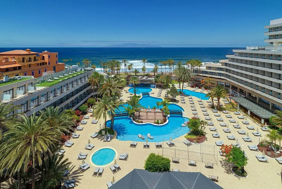 Luksusowy hotel z basenami i palmami, z widokiem na ocean. Idealne miejsce na wakacje na Playa de las Américas.