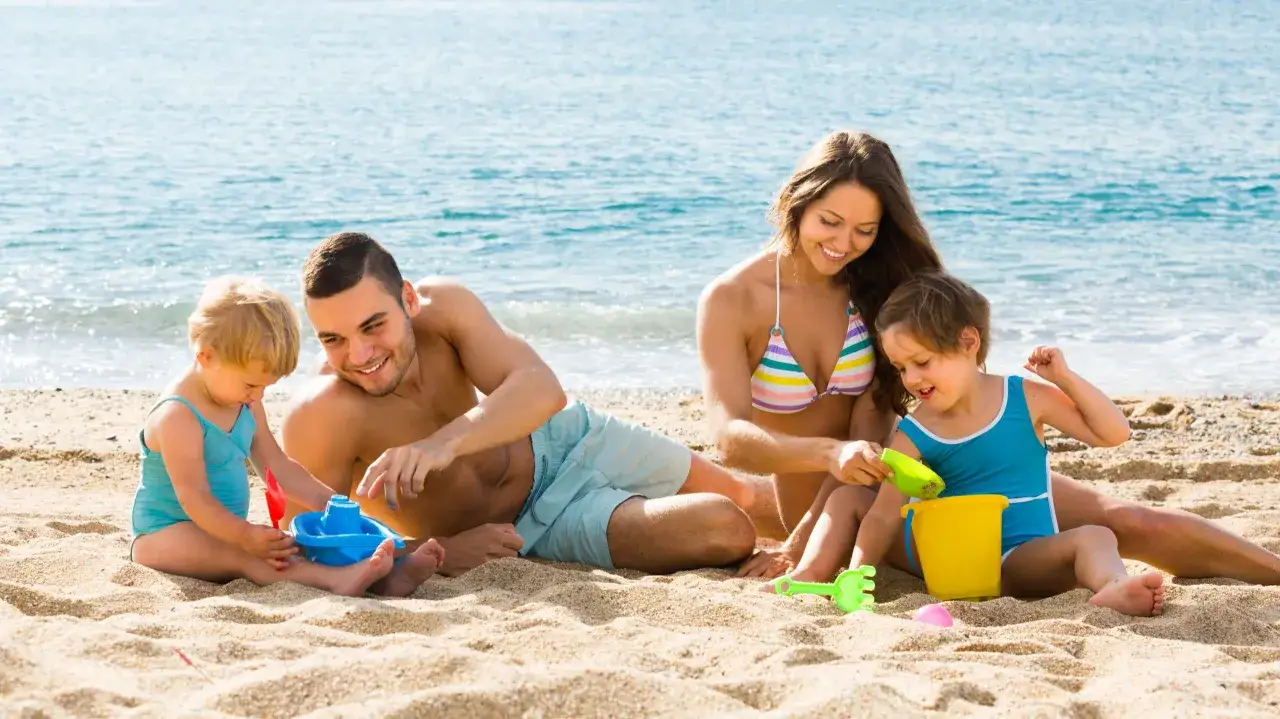 Rodzina buduje zamek z piasku na plaży. Idealne miejsce na wakacje z dziećmi.