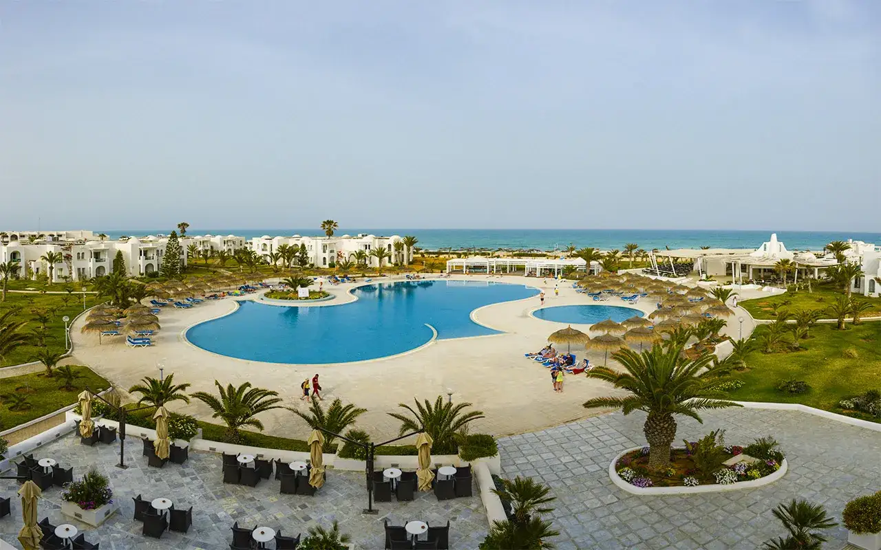 Basen i plaża w Vincci Helios Beach. Wiele osób odpoczywa, czytając opinie o hotelu.