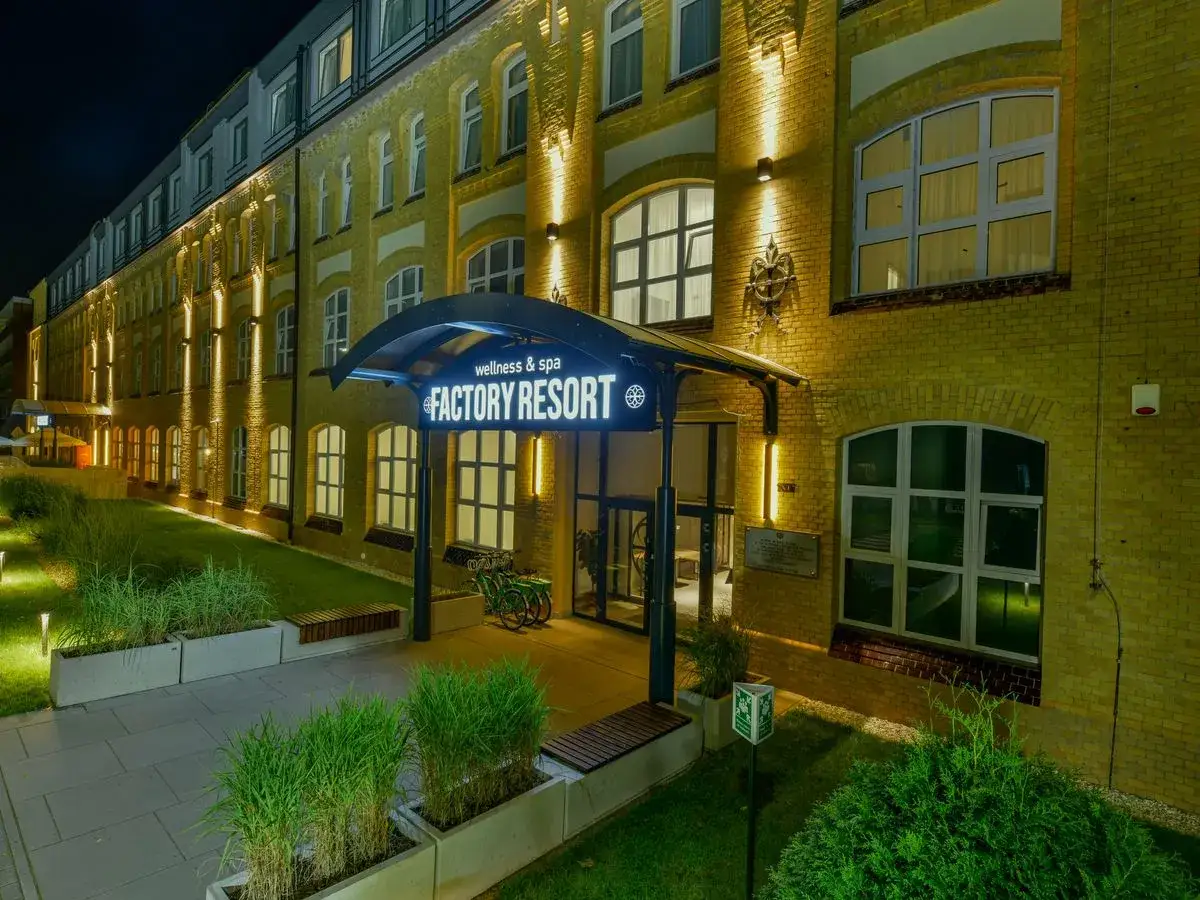 Factory Resort Wellness & Spa: nocne wejście do obiektu z podświetlaną nazwą. Wiele pozytywnych factory resort wellness & spa opinie potwierdza jego urok.