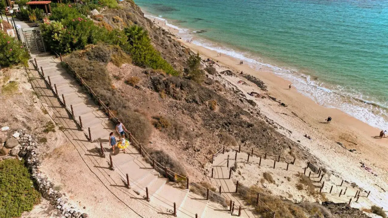 Rodzina schodzi schodami na plażę Fuerteventury. Tui magic life Fuerteventura opinie potwierdzają piękno tego miejsca.