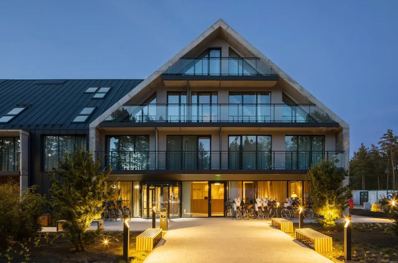Nowoczesny budynek Saltic Resort & Spa Łeba nocą. Opinie gości podkreślają jego architekturę i udogodnienia.