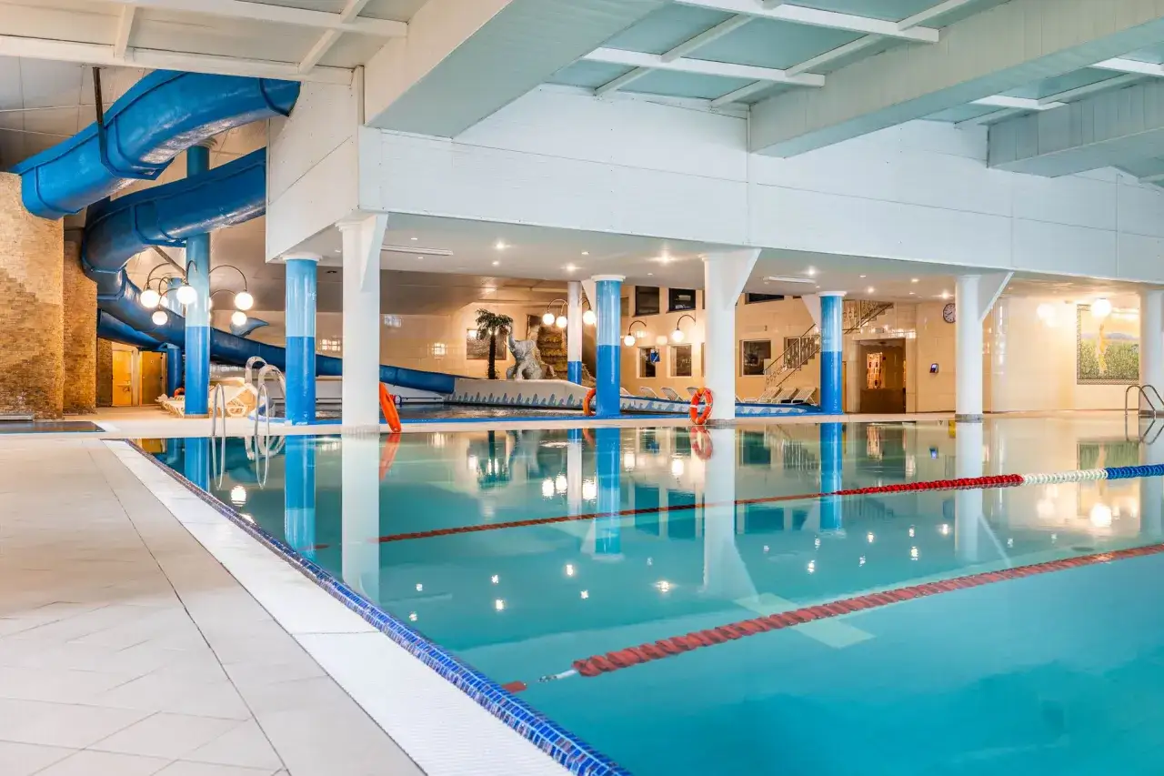 Basen z niebieską zjeżdżalnią i torami do pływania. Wiele osób szuka hotel gołębiewski białystok opinie, by sprawdzić atrakcje.