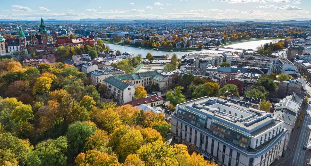 Jesień w Krakowie. Widok na Wawel, Wisłę i nowoczesny budynek Radisson Blu Hotel Krakow otoczony złotymi drzewami.