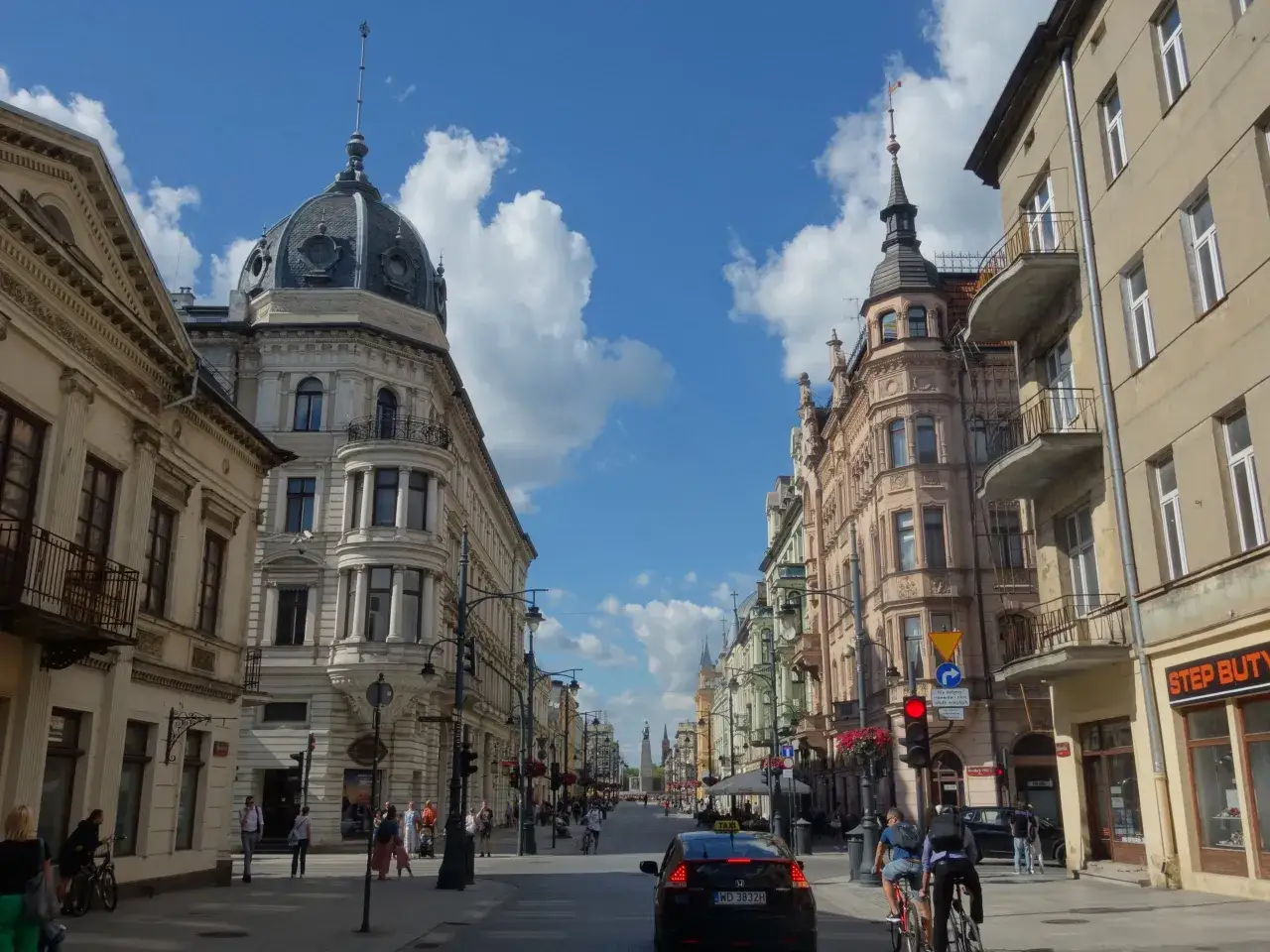 Spacer po Piotrkowska Łódź, podziwiając zabytkową architekturę i błękitne niebo z chmurami.