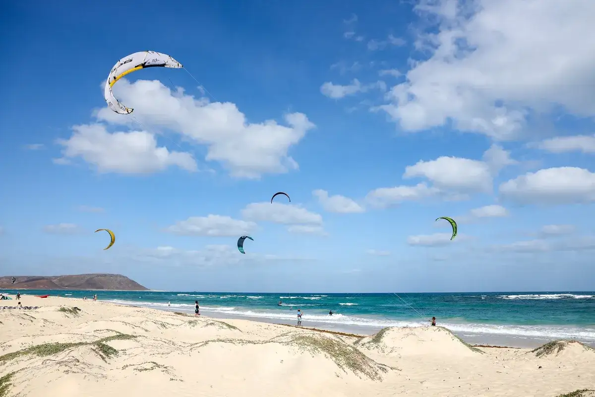 Wyspa Sal tętni życiem dzięki kitesurferom na turkusowym oceanie. Piękna plaża i błękitne niebo tworzą idealne warunki do sportów wodnych.