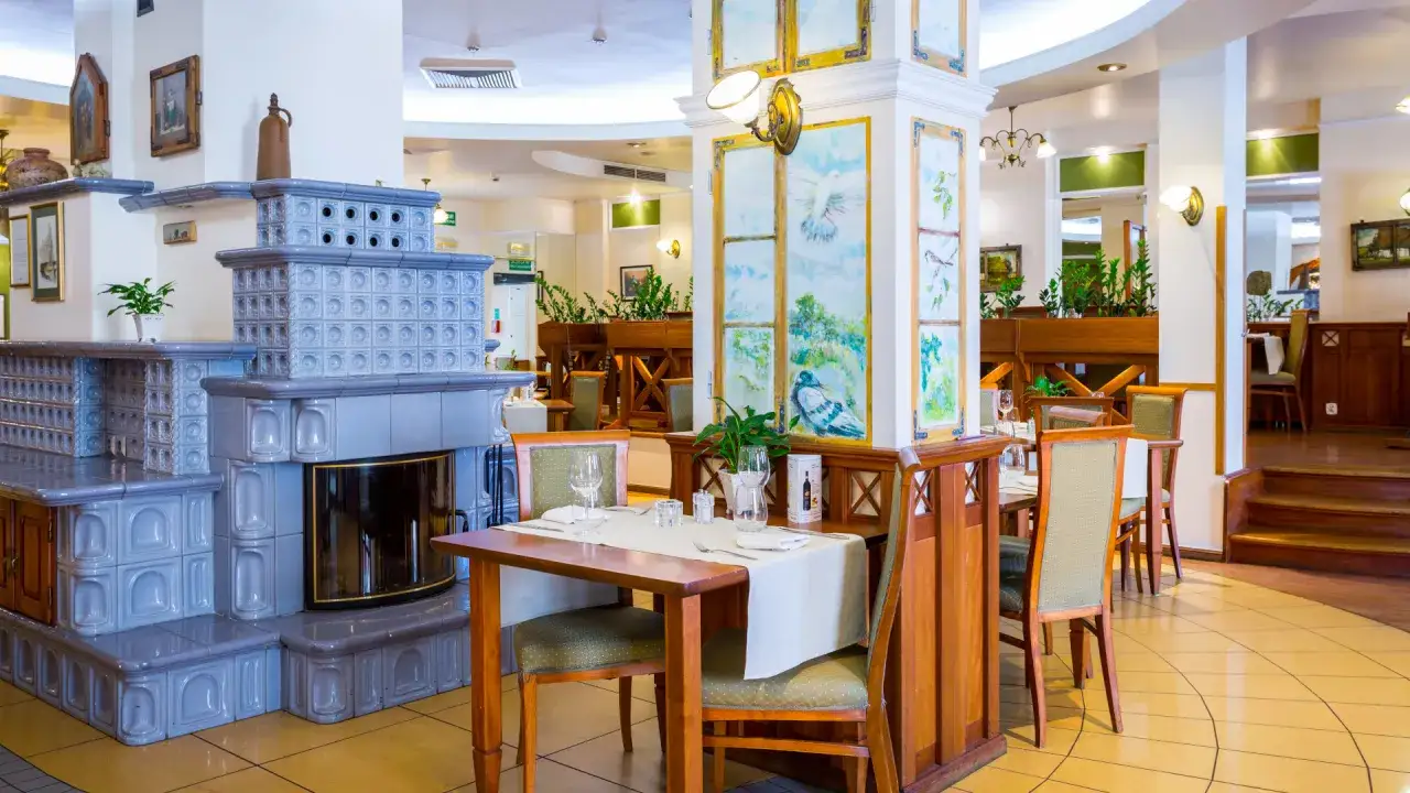 Przytulna restauracja hotelu Qubus Wrocław z kaflowym piecem i malowanymi panelami.