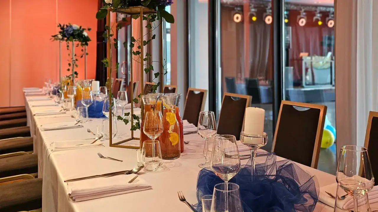 Elegancka sala bankietowa z długim stołem, dekoracjami i napojami. Idealne miejsce na przyjęcie, jak sugerują hotel swing opinie.