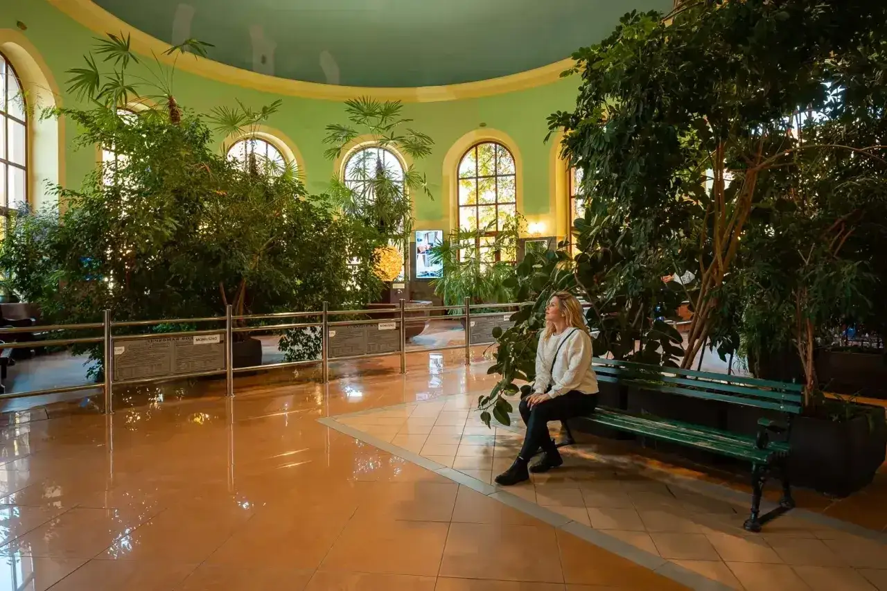 Kobieta odpoczywa w oranżerii, szukając pomysłów na wieczór w Kudowie-Zdroju.