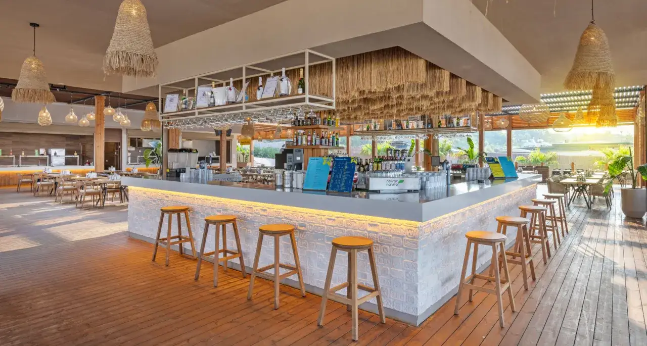 Nowe tui magic life jacaranda opinie: bar z drewnianymi stołkami i stołami, oświetlony słońcem.