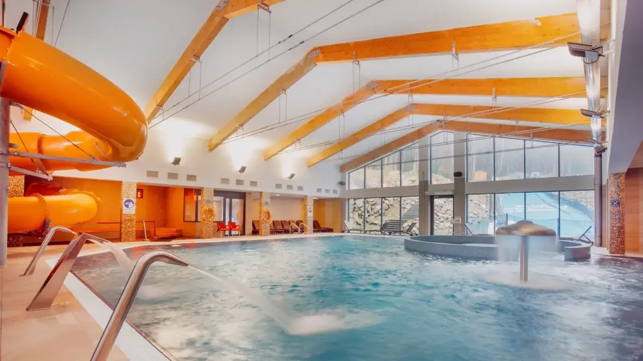 Basen z pomarańczową zjeżdżalnią i wodnymi atrakcjami. Wiele osób szuka takich miejsc, czytając blue mountain resort opinie.