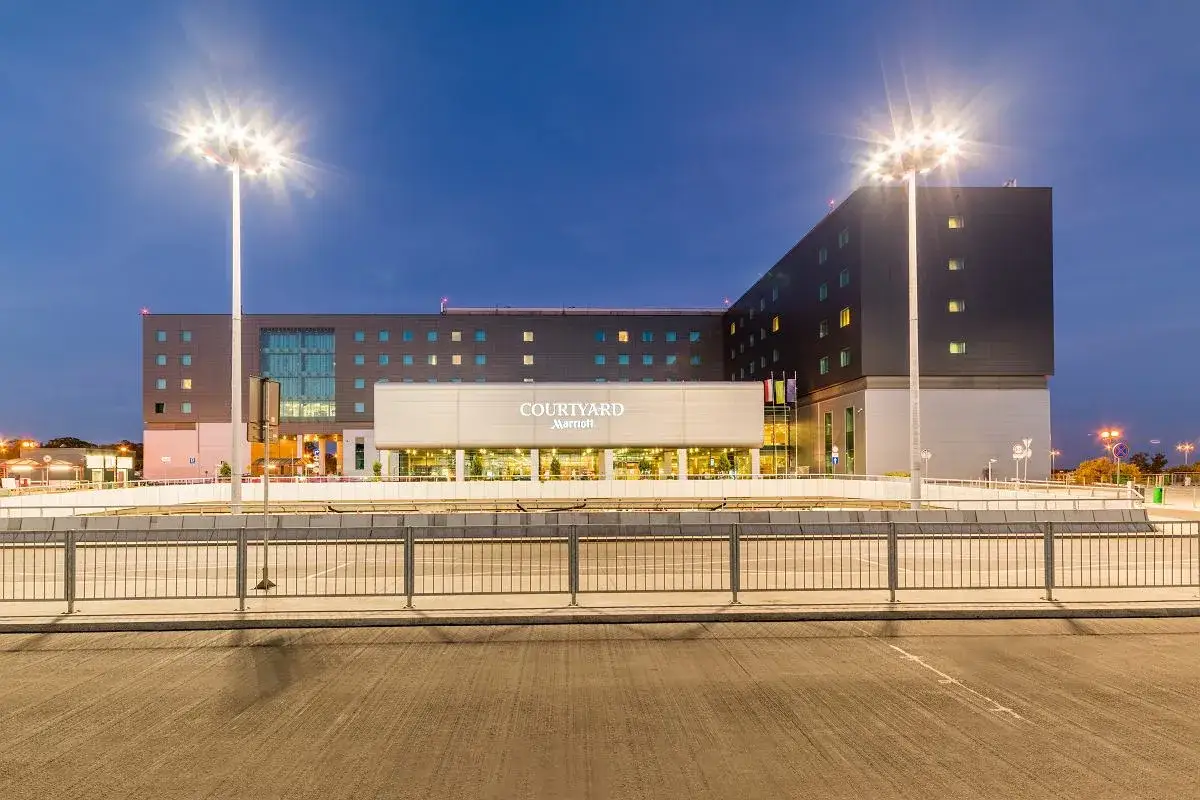 Nowoczesny Courtyard by Marriott, hotel lotniskowy w Warszawie, oświetlony nocą.