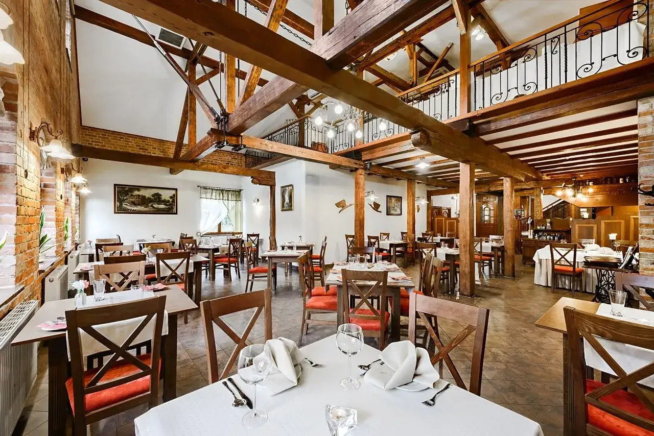 Przytulna restauracja w hotelu Młyn Elbląg. Drewniane belki, ceglane ściany i elegancko nakryte stoły tworzą wyjątkowy klimat.