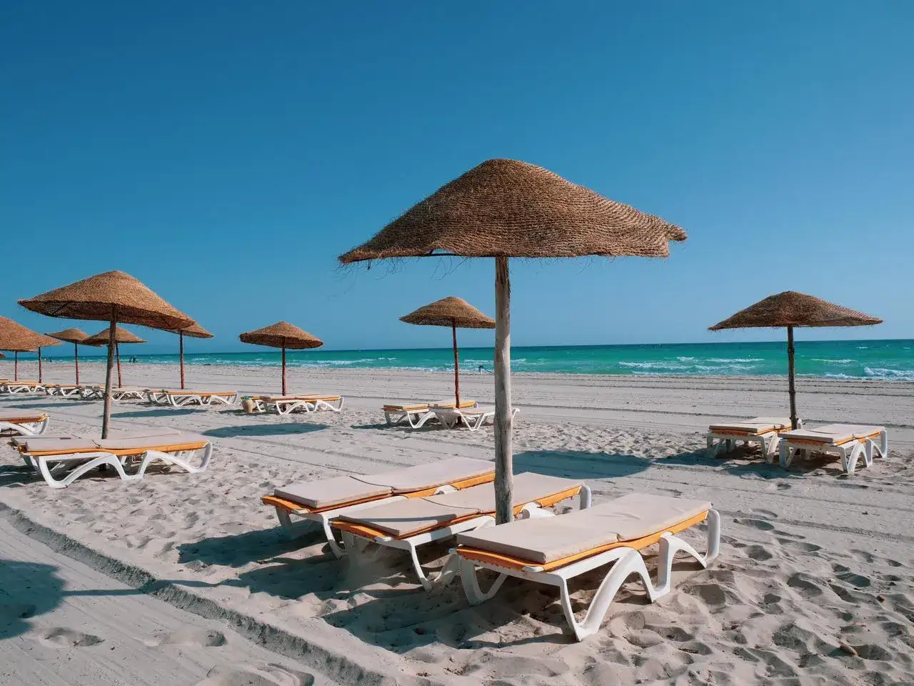 Pusta plaża z leżakami i parasolami. Idealne miejsce na relaks, zgodnie z wieloma djerba aqua resort opinie.