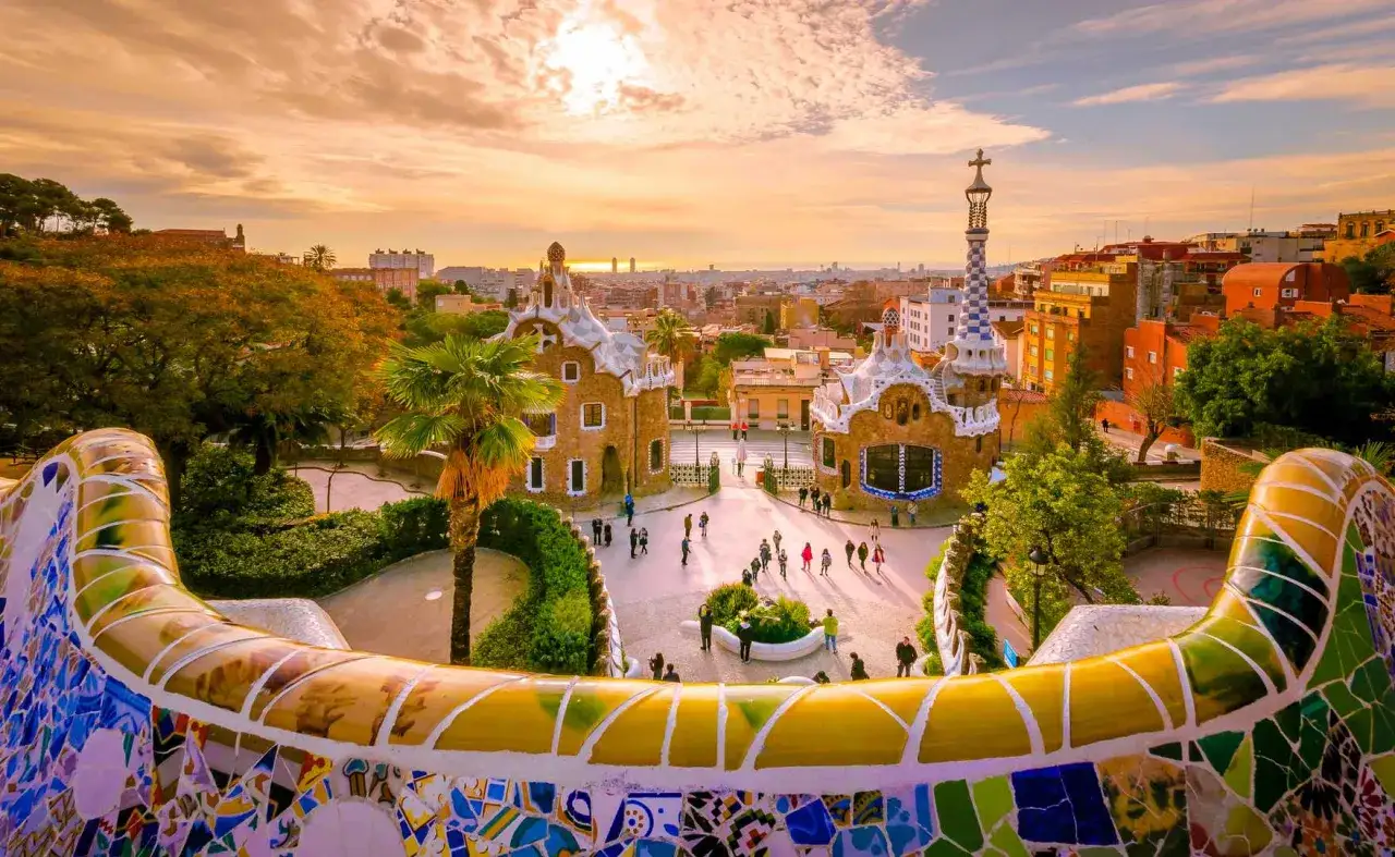 Park Güell w Barcelonie, jedna z najlepszych atrakcji w Hiszpanii, zachwyca mozaikową ławką i bajkowymi budynkami o zachodzie słońca.