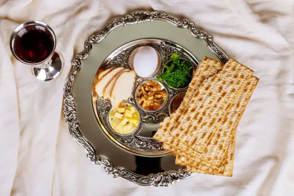 Talerz z symbolami jedzenia koszernego na Pesach: macą, jajkiem, warzywami i mięsem. Obok kielich z winem.