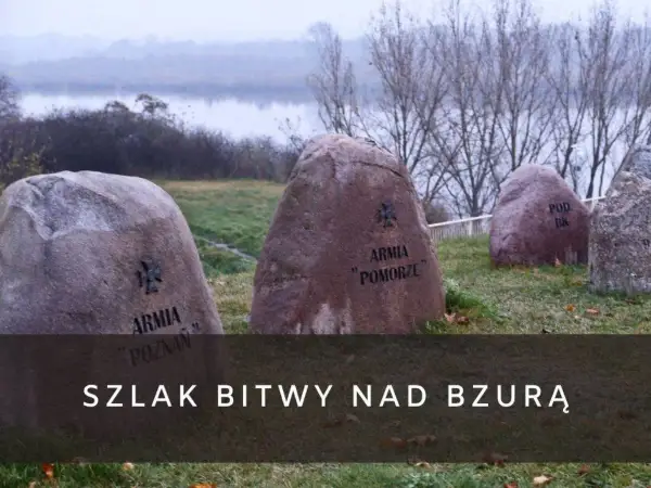 Kamienie pamięci z nazwami armii upamiętniają bitwę nad Bzurą. W tle rzeka i drzewa.