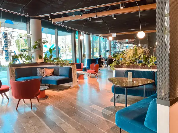 Nowoczesne wnętrze hotelu Puro w Łodzi z wygodnymi, turkusowymi sofami i czerwonymi fotelami.