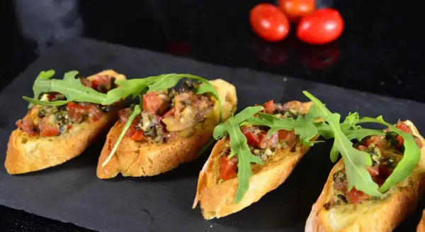 Cztery chrupiące bruschetty z pomidorami, ziołami i rukolą. Idealne tapas, co to jest? Pyszna przekąska!