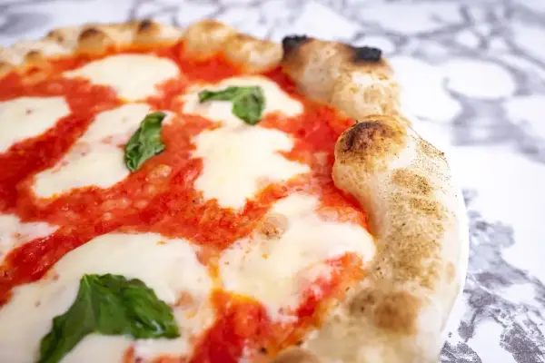 Pyszna pizza parma z rozpływającym się serem mozzarella, sosem pomidorowym i świeżą bazylią. Idealna na włoską ucztę.