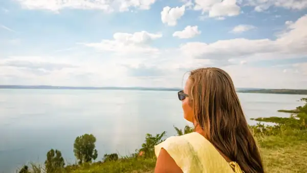 Kobieta w żółtej bluzce podziwia rozległe jezioro Balaton.