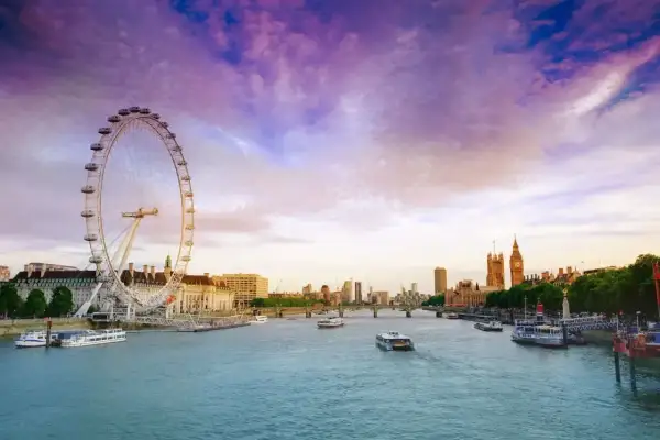 Zachód słońca nad Tamizą, z widokiem na London Eye i Parlament. Rzeka w Londynie lśni w purpurowym niebie.