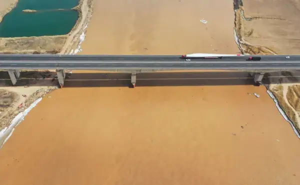 Most gigantycznego łopaty wiatraka transportowany przez most nad mętną wodą rzeki Huang He.