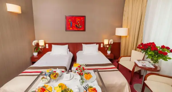 Pokój hotelowy z dwoma łóżkami, śniadaniem na tacy i bukietem róż. Idealne miejsce na pobyt, zgodnie z premier kraków hotel opinie.