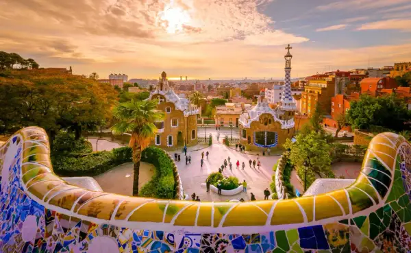 Park Güell w Barcelonie, jedno z najlepszych miast do odwiedzenia w Hiszpanii, zachwyca mozaikową ławką i bajkowymi budynkami o zachodzie słońca.