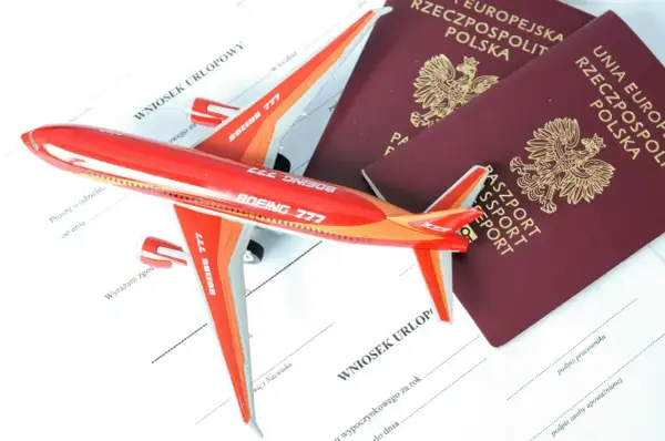 Czerwony samolot i dwa polskie paszporty leżą na wniosku urlopowym. Czy do Albanii potrzebny jest paszport? Sprawdź!