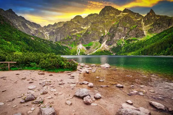 Górskie jezioro Morskie Oko, jedno z najpiękniejszych miejsc w Polsce, otoczone zielonymi zboczami i skalistymi szczytami.