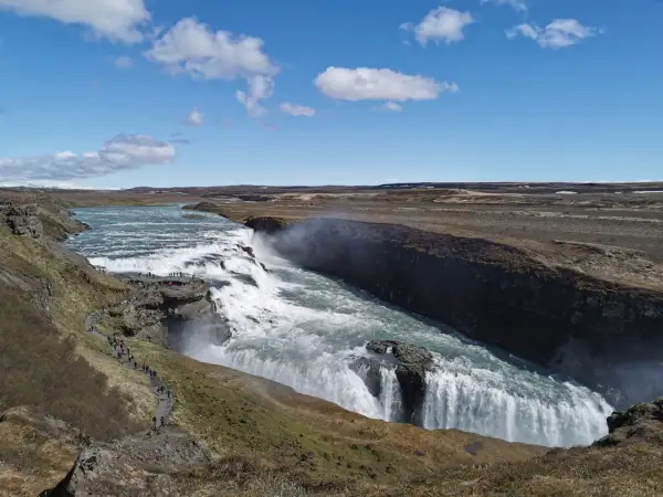 Potężny wodospad Gullfoss, część islandzkiego Złotego Kręgu, z turystami na ścieżce widokowej.