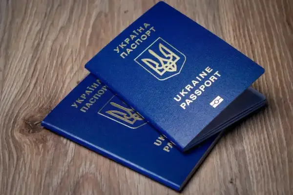 Dwa niebieskie paszporty Ukrainy leżą na drewnianym blacie. Czy do Turcji potrzebny jest paszport? Tak, do podróży potrzebny jest paszport.