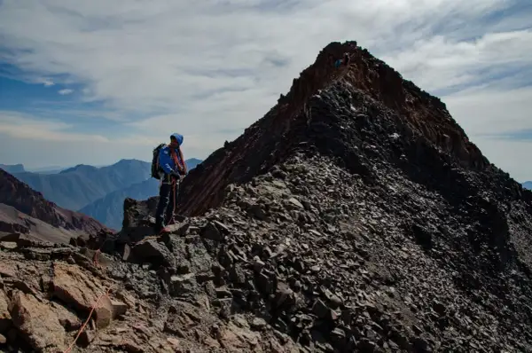 Alpinista na grani, zbliża się do najwyższego szczytu Gruzji. W tle pasmo górskie.
